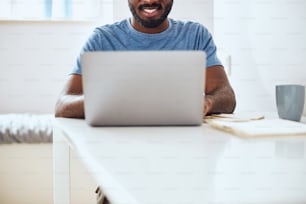 Foto ritagliata di un cittadino multietnico che svolge il suo lavoro a casa sul suo computer