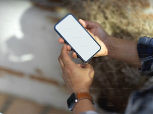 Abgeschnittene Aufnahme von männlichen Händen mit Smartphone beim Entspannen im Garten, einschließlich Clipping-Pfad