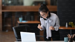 Femme heureuse et excitée à lunettes, lisez de bonnes nouvelles en ligne sur un ordinateur portable et célébrez la réalisation de vos objectifs.
