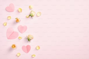 Composizione flat lay con cuori di carta, fiori di rosa e petali su fondo rosa. Romantico, amore, concetto di San Valentino. Vista dall'alto con spazio di copia.