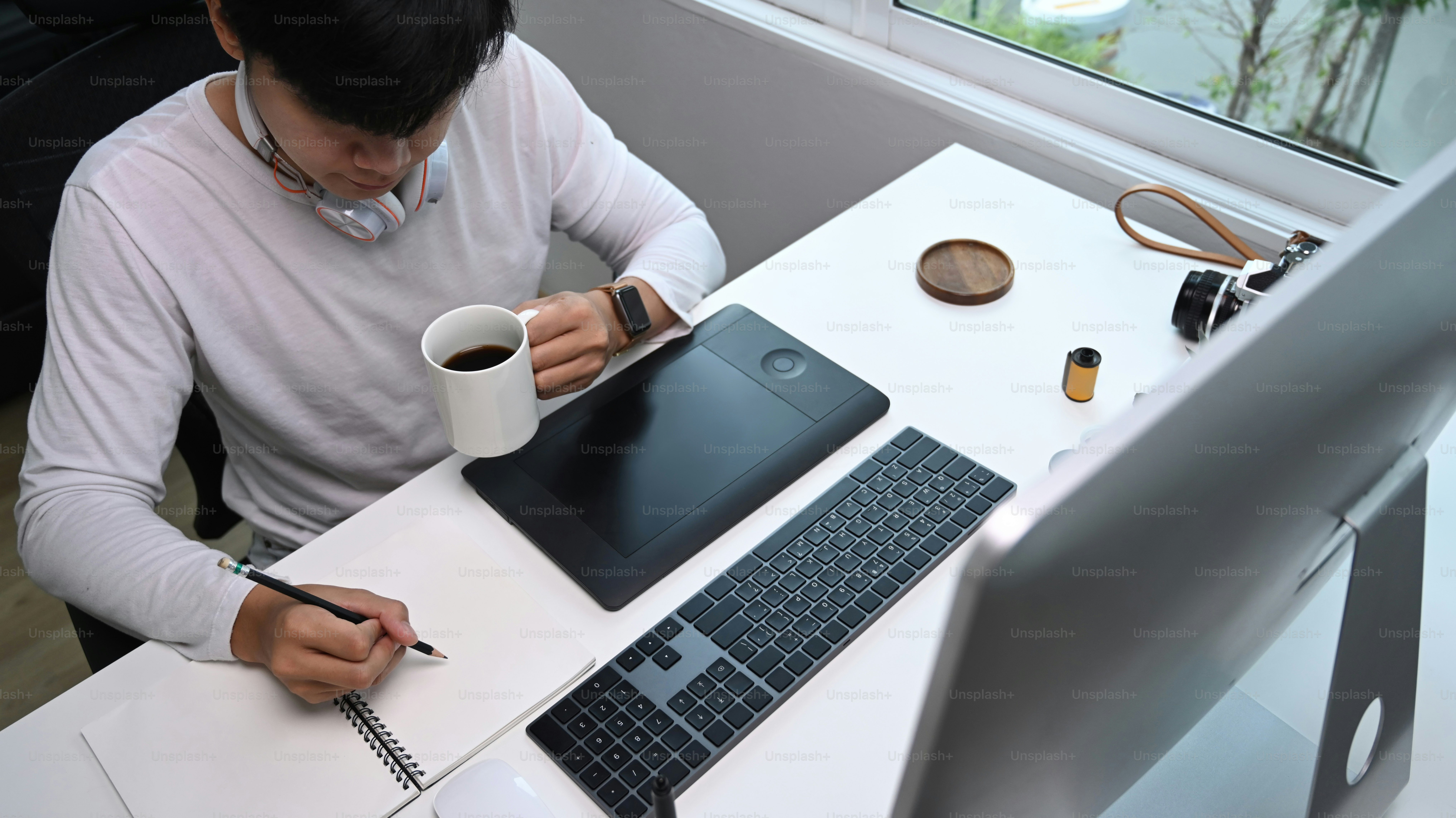 person working creatively on laptop at desk with coffee, soft natural light, minimal workspace