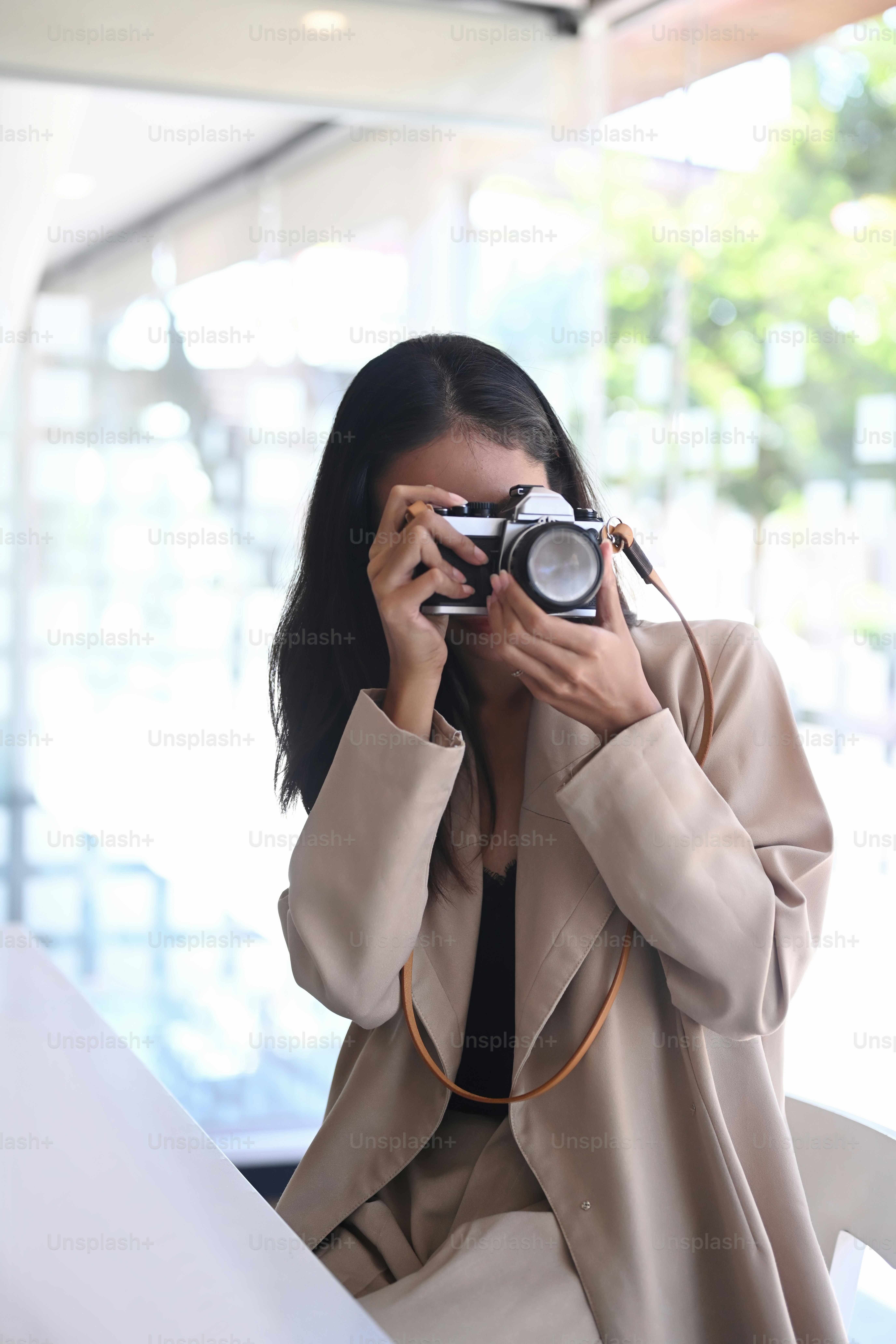 Retrato de una joven asiática que toma una foto con una cámara digital en su estación de trabajo.