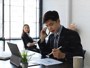 Portraits of businessman talking on the phone while working with paperwork in office room