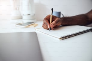 Persona che tocca un foglio di un blocco note con una penna e scrive alcune informazioni