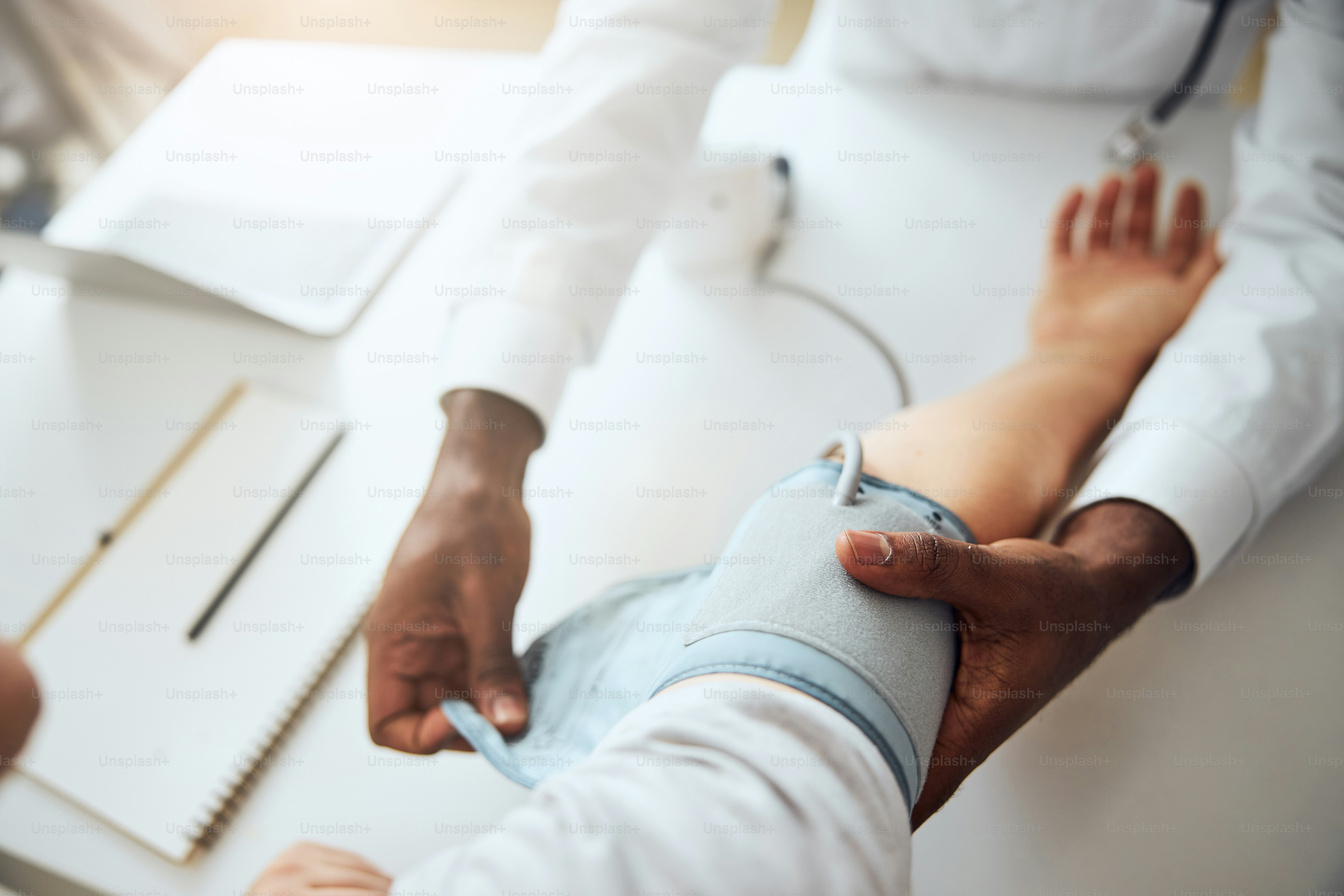 Doctor putting a cuff of a blood pressure monitor on a patient stretched hand