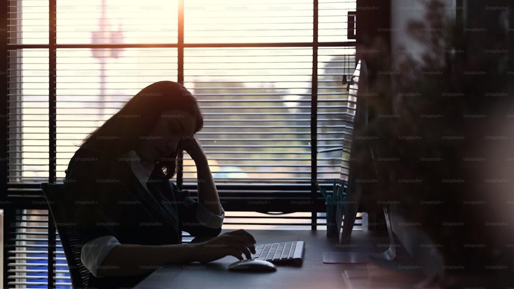 Businesswoman in black suit feeling tired and stressed while sitting at in office.