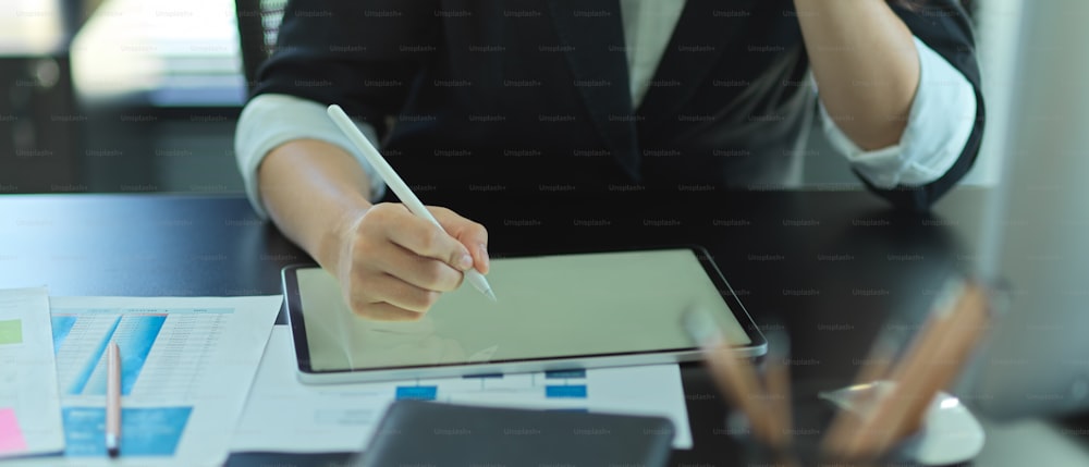 Close up view of businesswoman working with tablet and paperwork on office desk