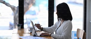 Vue latérale d’une femme d’affaires travaillant sur une tablette à un bureau de travail dans un bureau moderne.