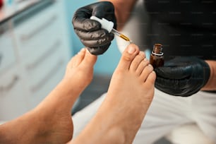 Competent podiatrist using oil for doing foot massage after finishing medical pedicure