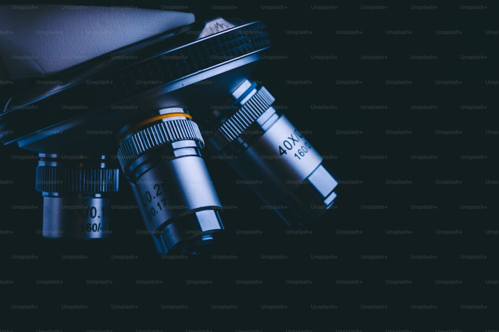 Closeup de microscópio com lente metálica, análise de dados em laboratório, equipamento científico em biologia, química, médico para cientistas ou estudante em educação