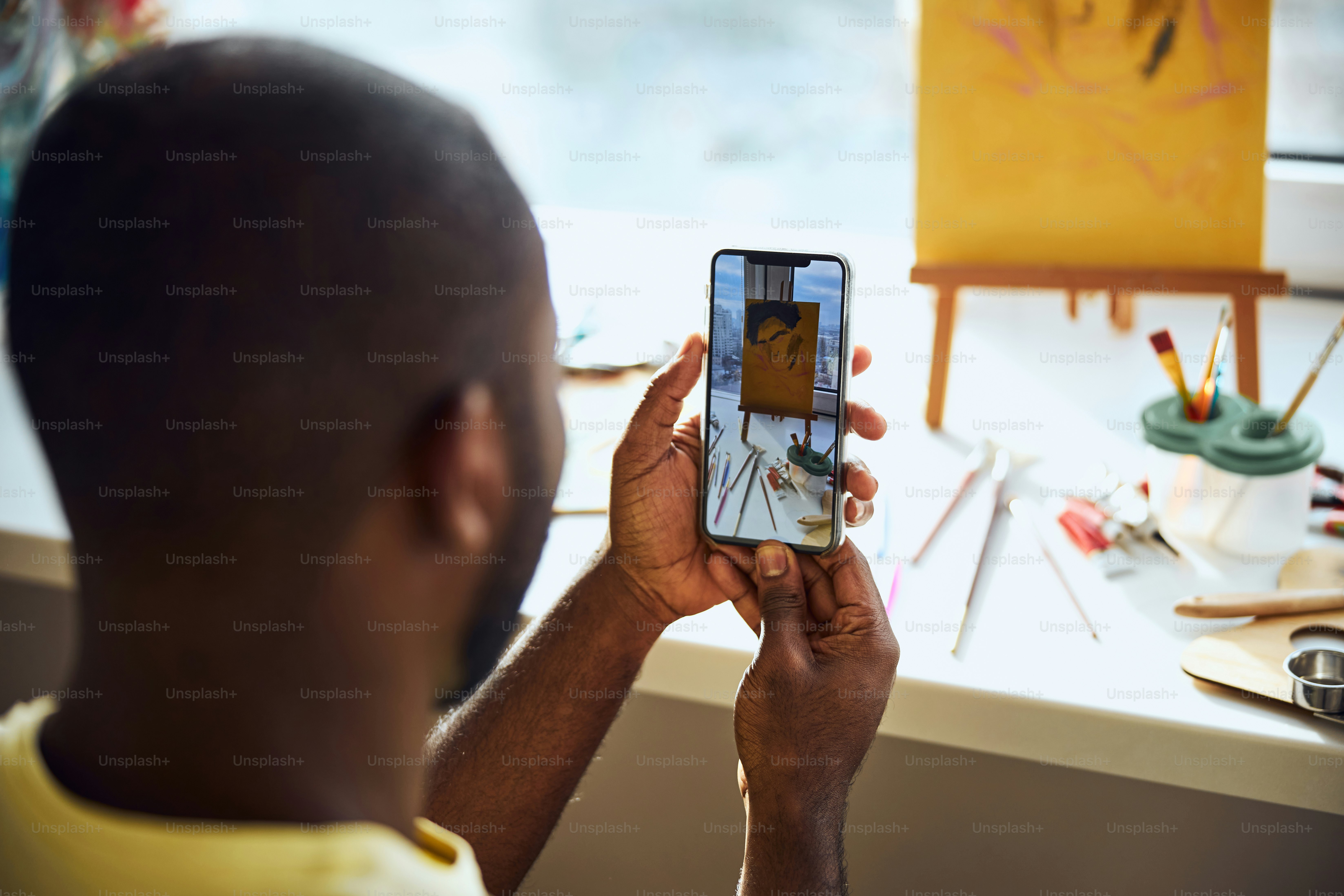 Persona que toma una foto de un dibujo y pinta electrodomésticos en un teléfono celular y observa el resultado