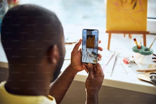 Person taking a photo of a drawing and painting appliances on a cellphone and watching the result