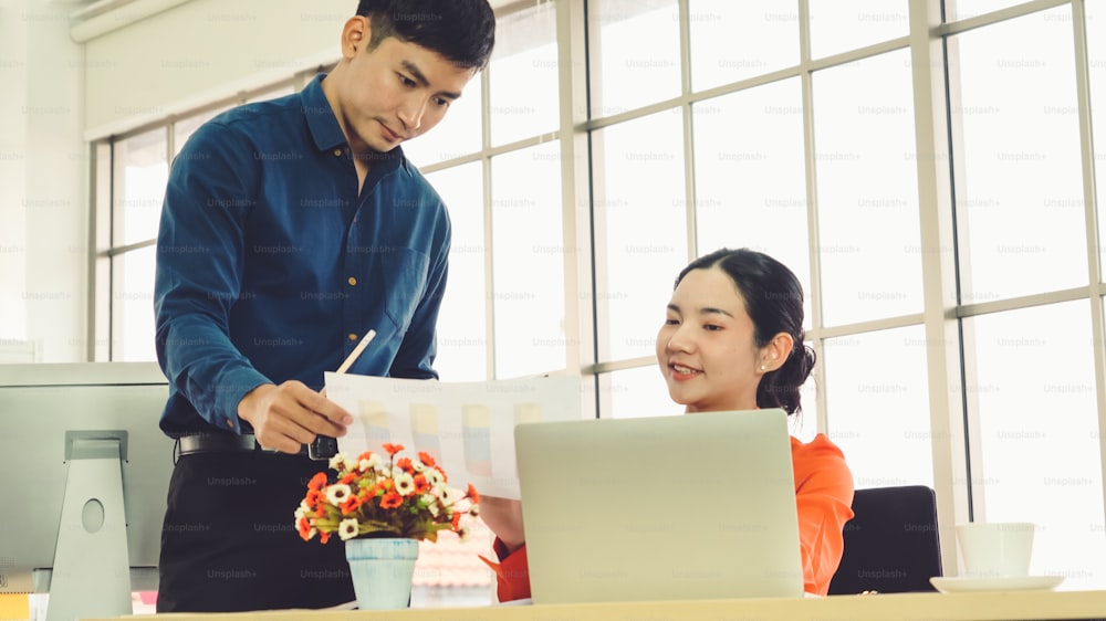 Two business people talk project strategy at office meeting room. Businessman discuss project planning with colleague at modern workplace while having conversation and advice on financial data report.