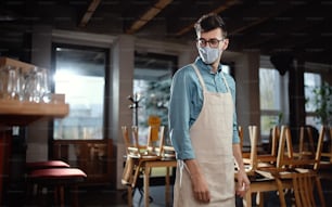 Frustrated waiter standing in closed cafe or coffee shop, small business lockdown due to coronavirus.