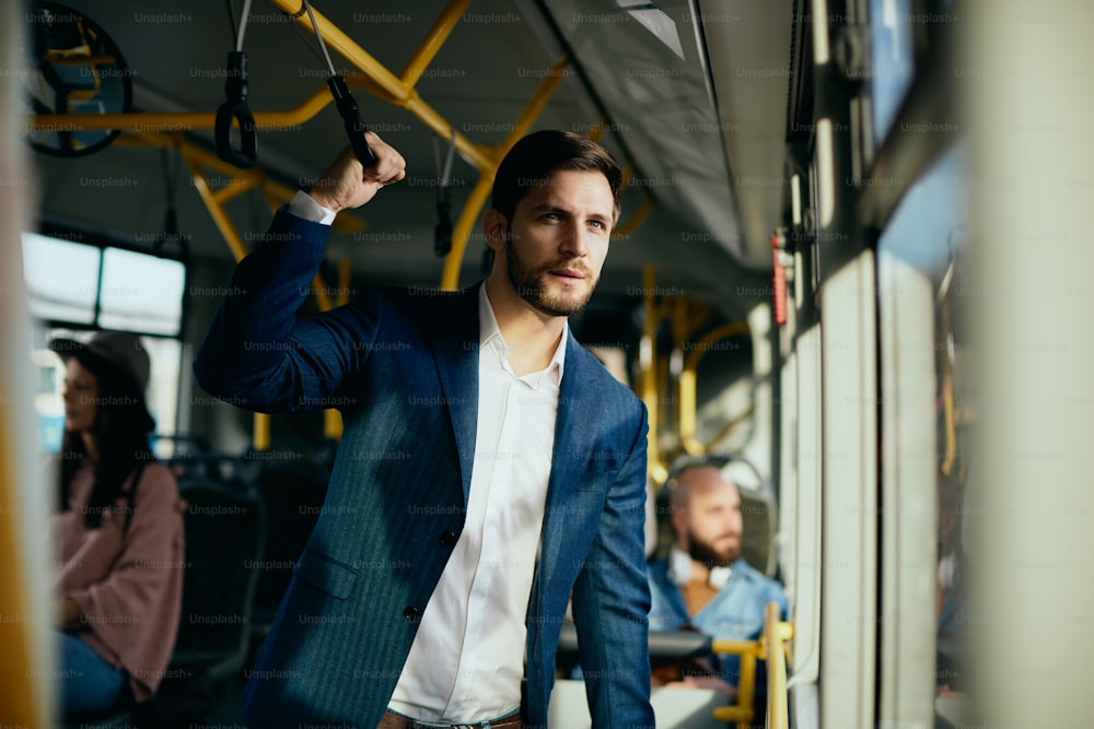 Empresario masculino mirando por la ventana mientras viaja al trabajo en autobús.