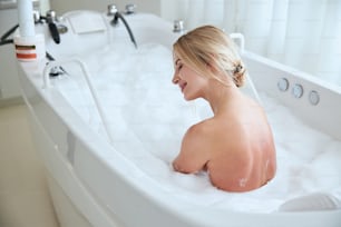 Retrato de vista lateral de una mujer serena que tiene ocio en el agua en el centro de spa de la esteticista