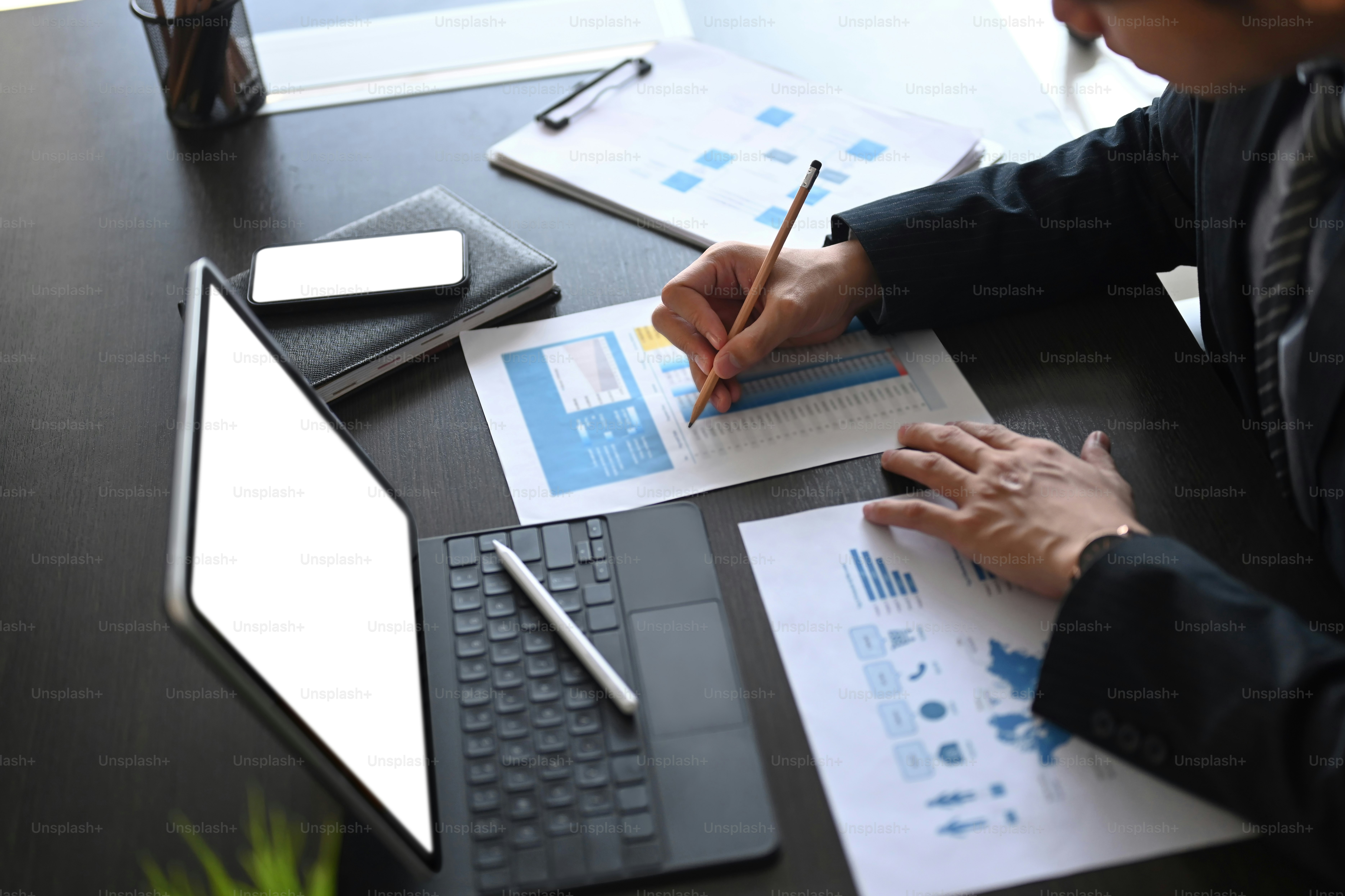 Cropped shot of businessman doing paperwork at workplace and using ...