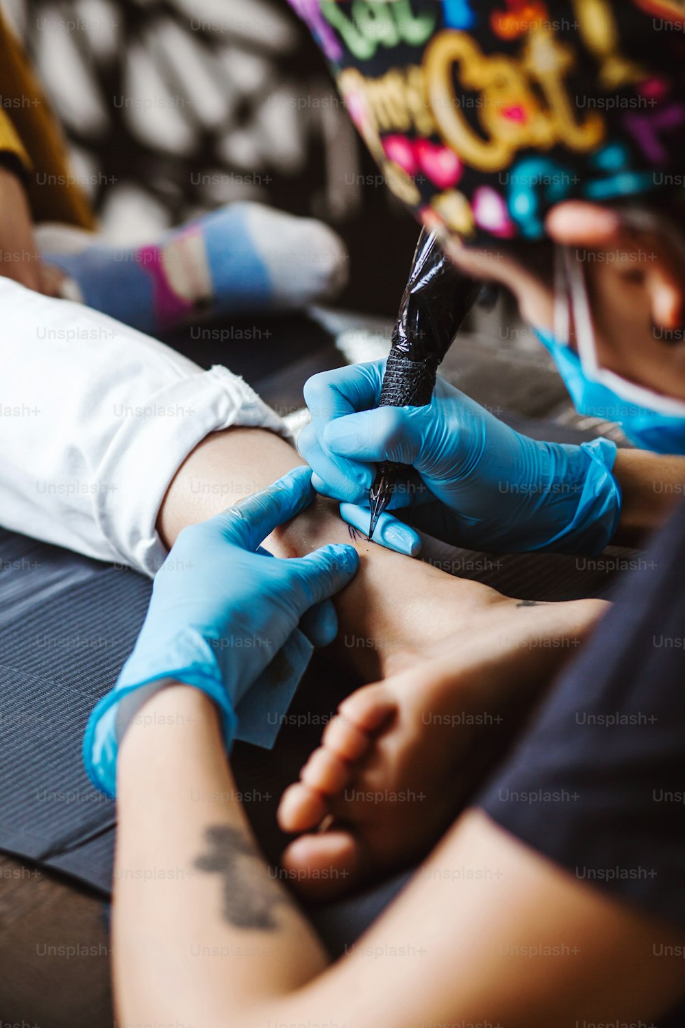 Latin woman tattoo artist demonstrates the process of getting tattoo with paint and works in blue sterile gloves in Mexico city