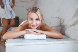 Portrait en gros plan d’une charmante jolie dame au sourire mignon se relaxant et profitant d’une excellente procédure de spa dans un centre de beauté