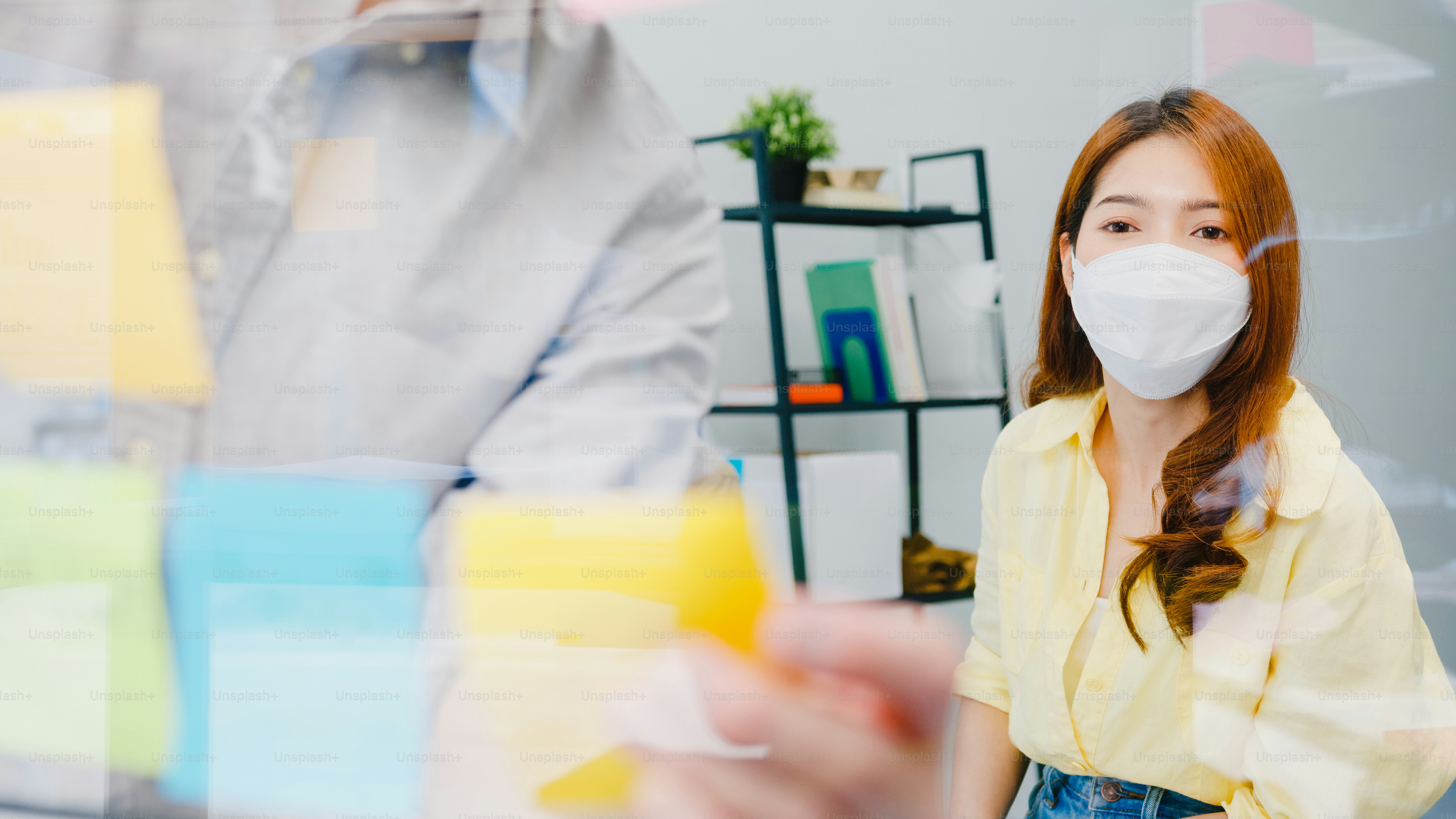 Asia businesspeople meeting brainstorming ideas conducting business presentation ideas project colleagues and wear protective face mask back in new normal office. Lifestyle and work after coronavirus.