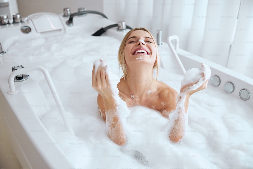 Portrait en gros plan d’une femme caucasienne souriante heureuse passant un excellent week-end dans une station thermale tout en prenant un bain le matin