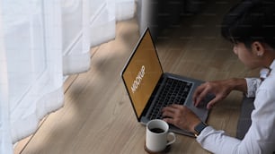 Over head shot of young man freelance lying on floor and working with laptop computer at home.