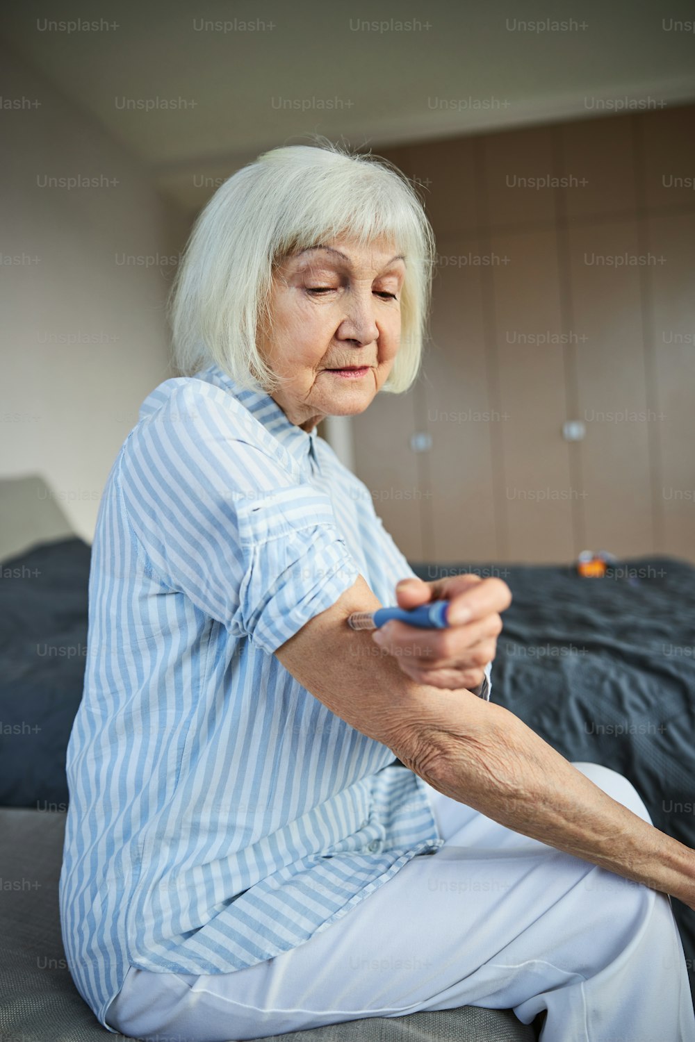 Une femme âgée bouleversée met son doigt sur un piston et fait une injection dans une chambre à coucher