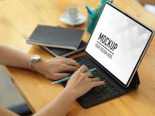 Abgeschnittene Aufnahme von weiblichen Händen, die auf der Tablet-Tastatur tippen, während sie im Büroraum arbeiten