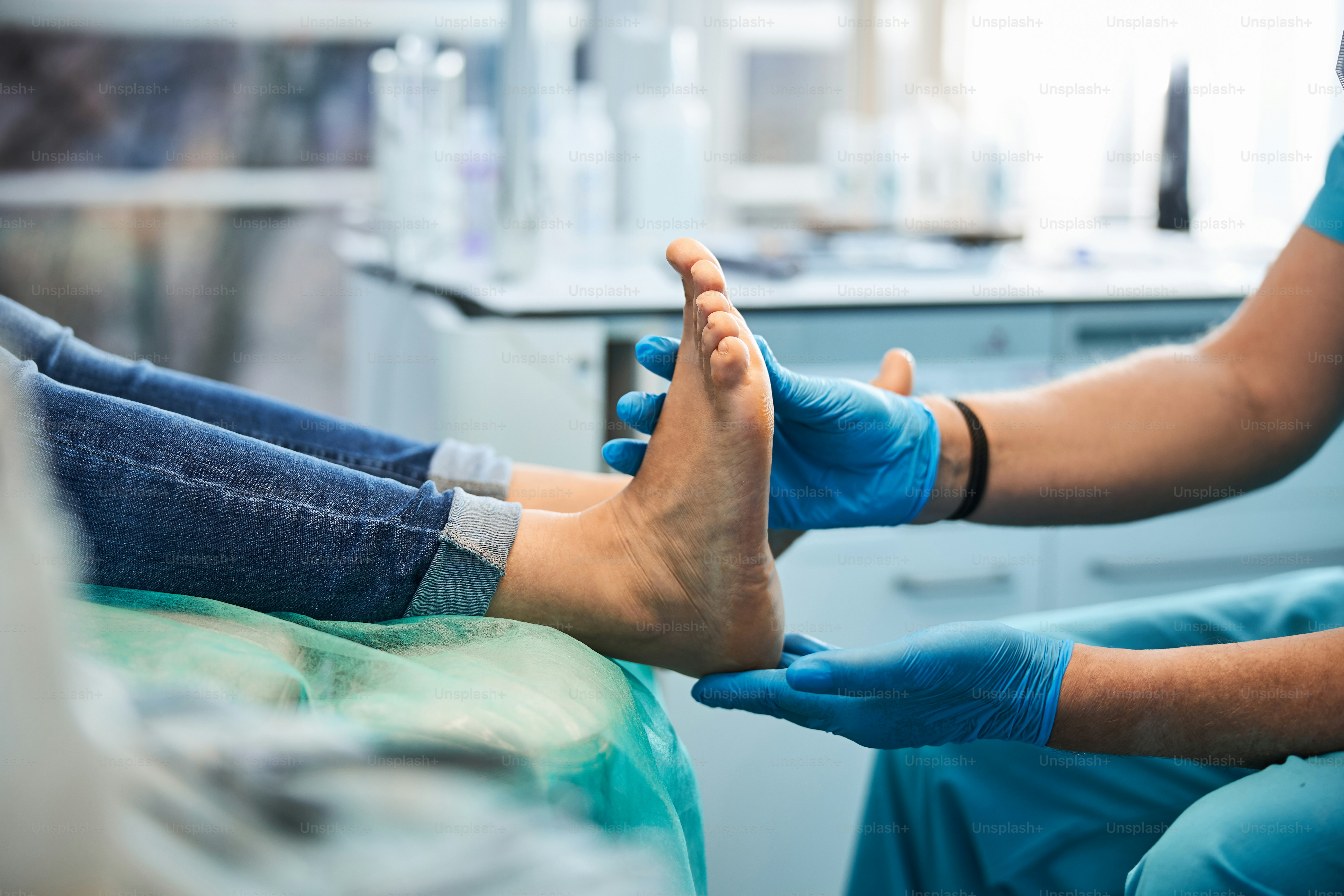Potret kaki wanita di kursi medis dengan tampilan samping dekat saat ahli podi profesional memeriksanya di klinik kecantikan