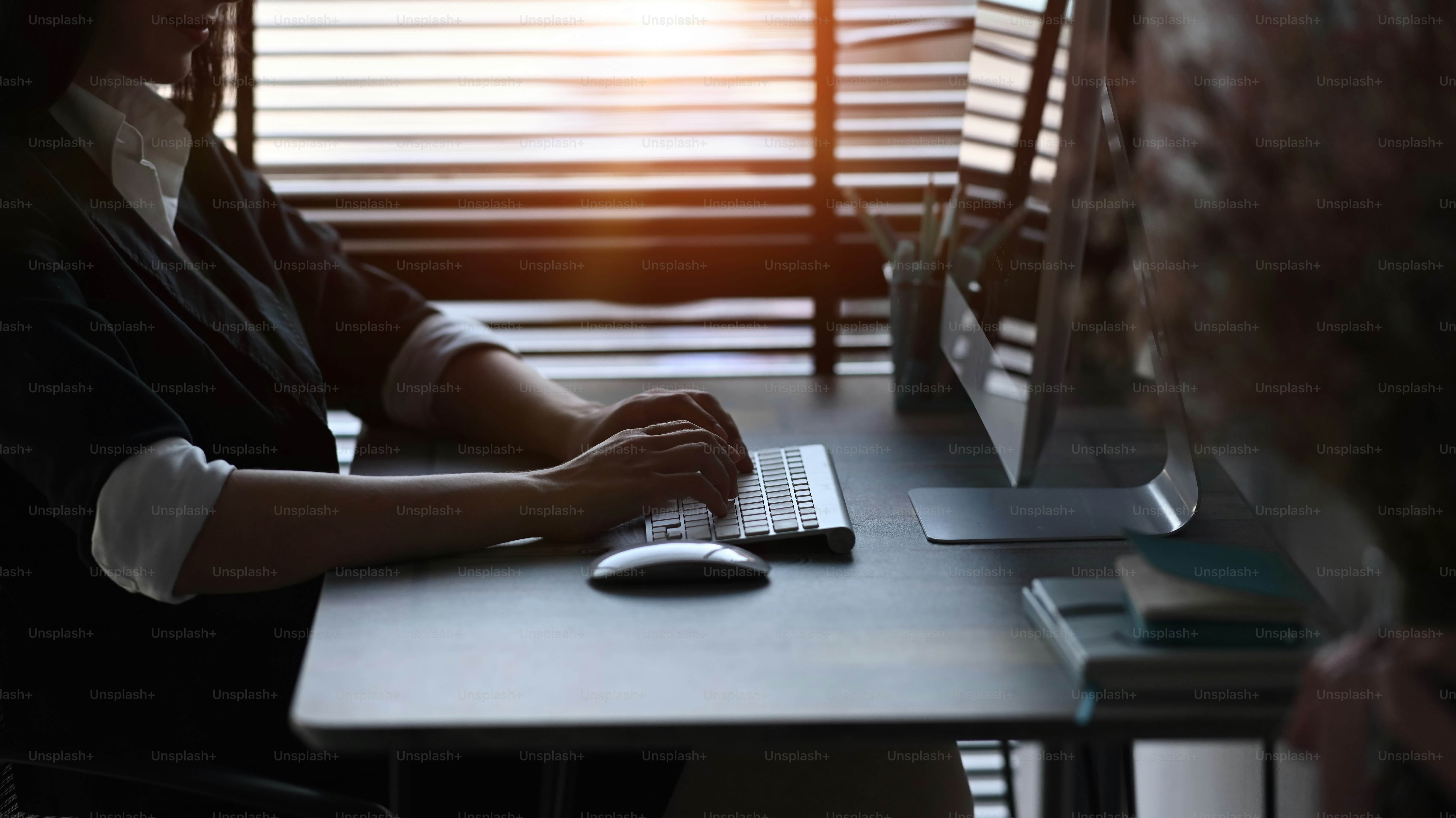 Side view of woman office worker working with computer and sitting by the window in office.