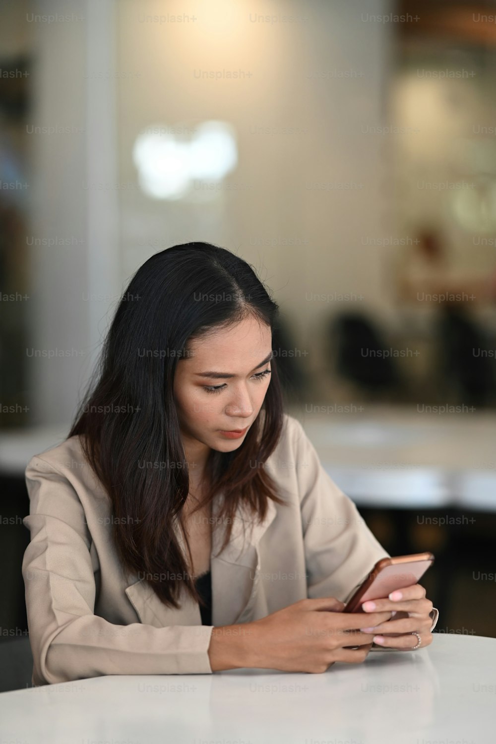 Portrait of businesswoman sitting in office room and using smart phone checking social media.