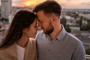 Retrato de cerca, hombre y mujer sonriendo el uno al otro en la puesta del sol con la ciudad en el fondo. Momentos íntimos románticos en pareja