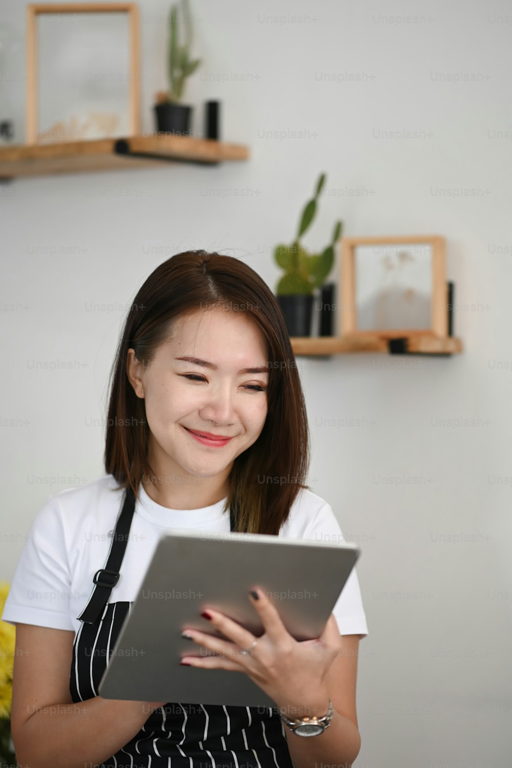 Ritratto di donna proprietaria di successo e utilizzando la tavoletta digitale mentre è seduta nella sua caffetteria.