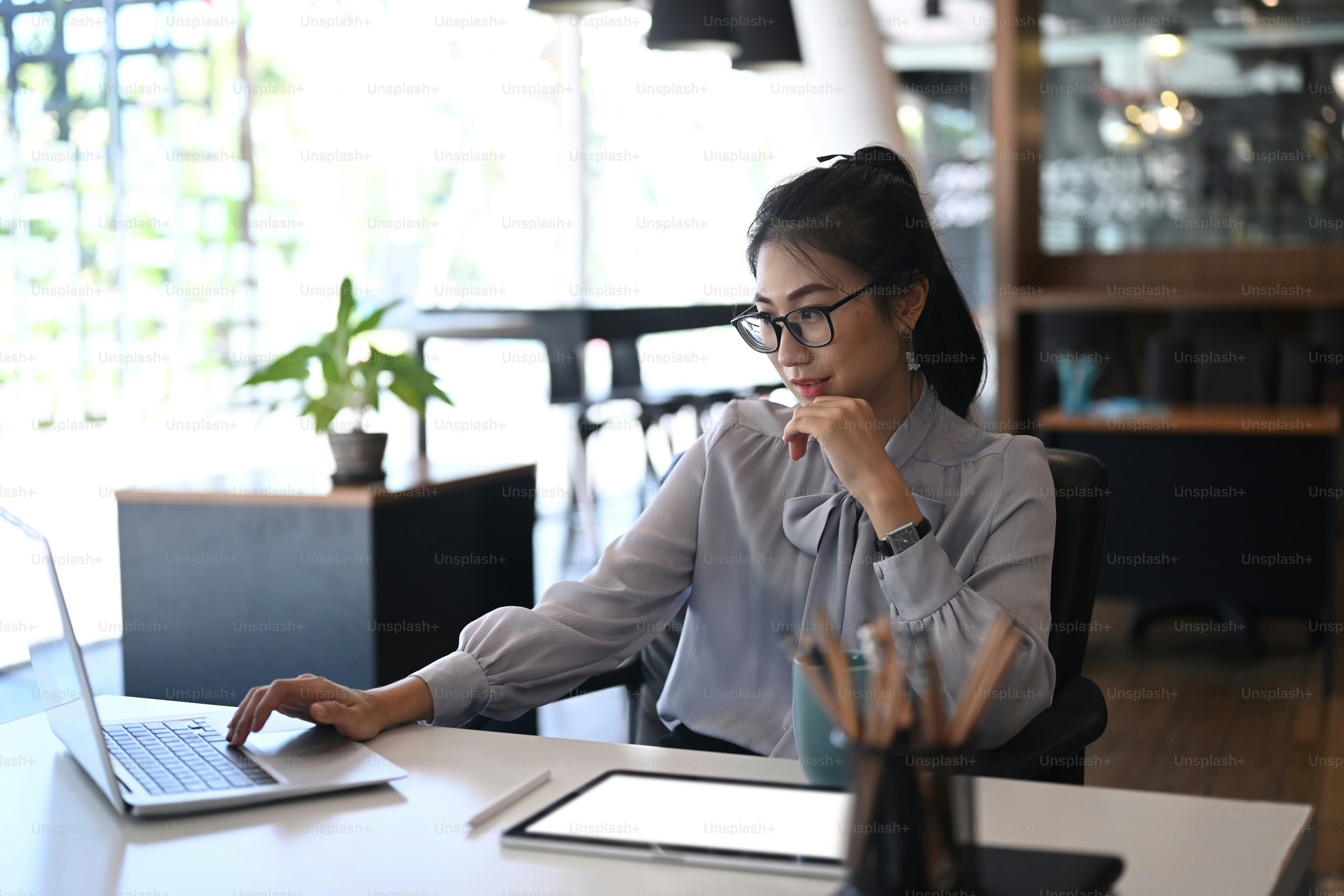 Businesswoman in eye glasses using computer laptop for online software ...