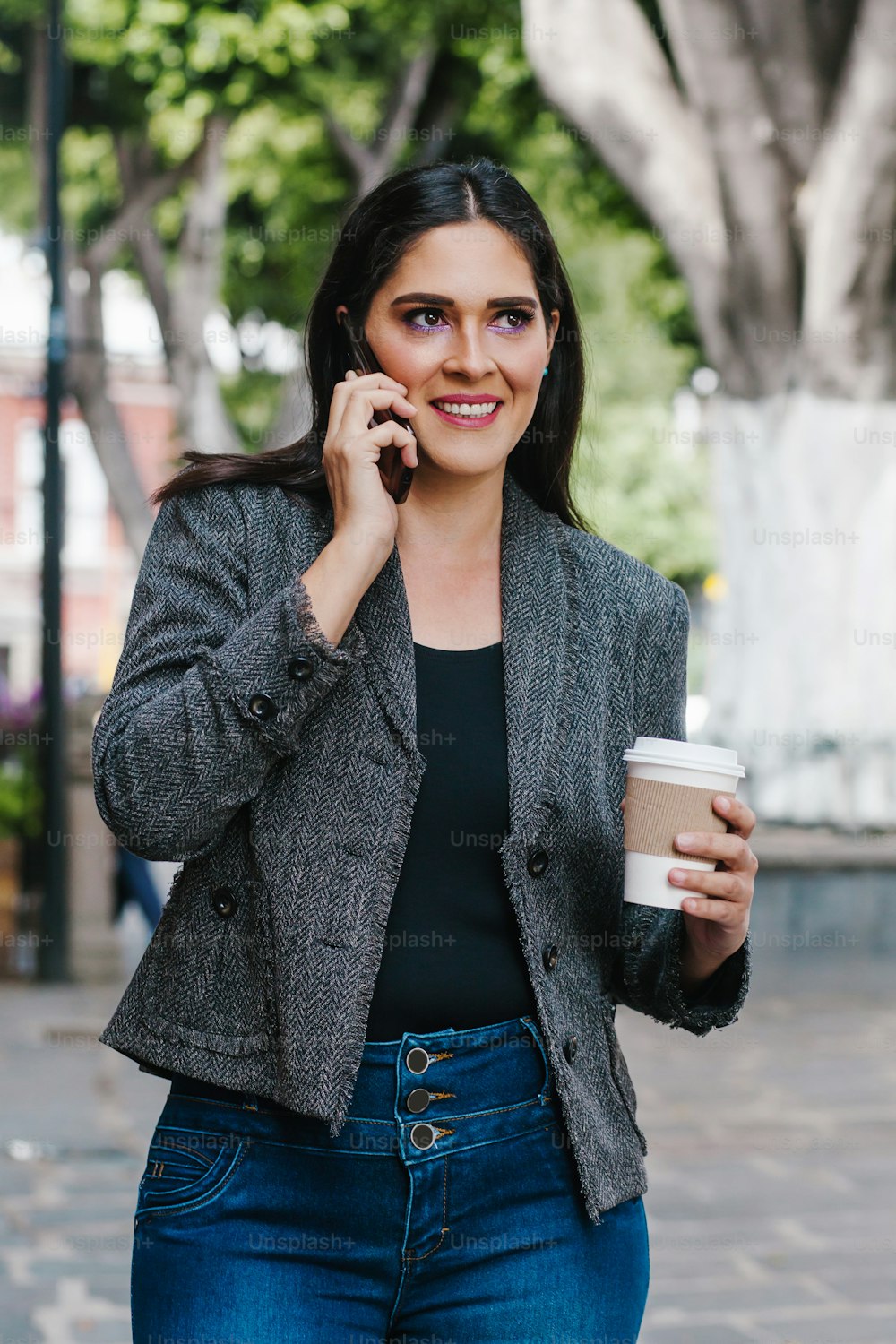 Donna d'affari messicana che parla al telefono mentre cammina in una città dell'America Latina