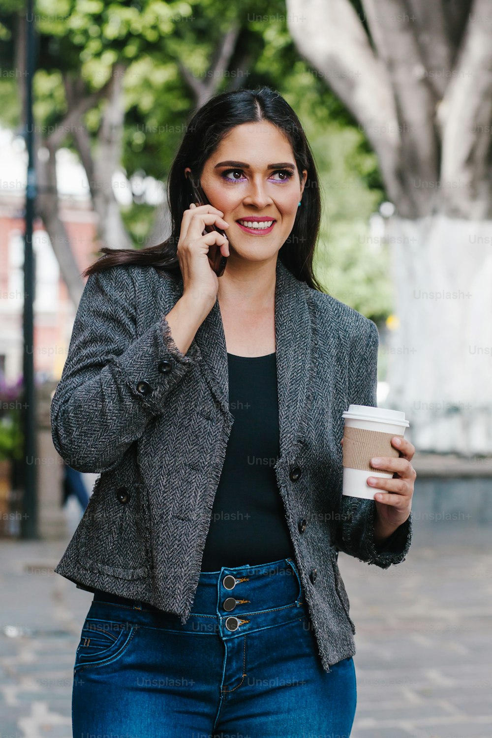 Mexican business woman talking by phone while she is walking in a Latin America city