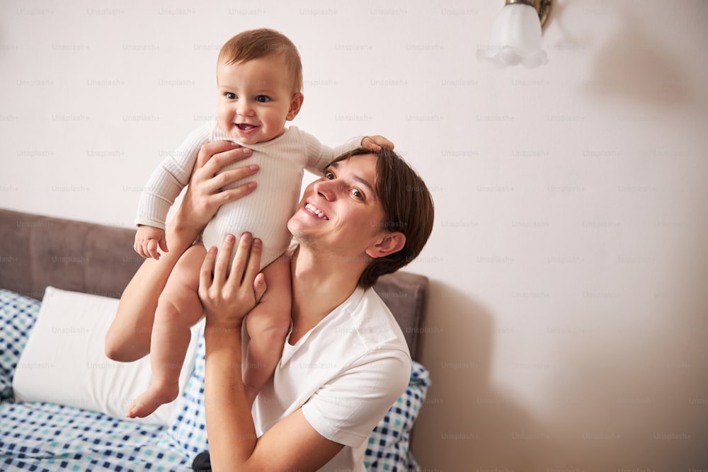 Positive delighted father demonstrating his smile while enjoying his first feelings of parenthood