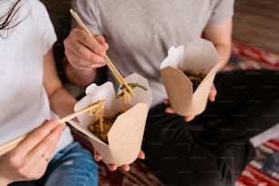 Close up couple hands have good time together at home while eating Chinese food