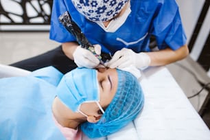 Cosmetologo latino che si prepara alla donna messicana per la procedura di trucco permanente del sopracciglio in Messico, primo piano di Microblading