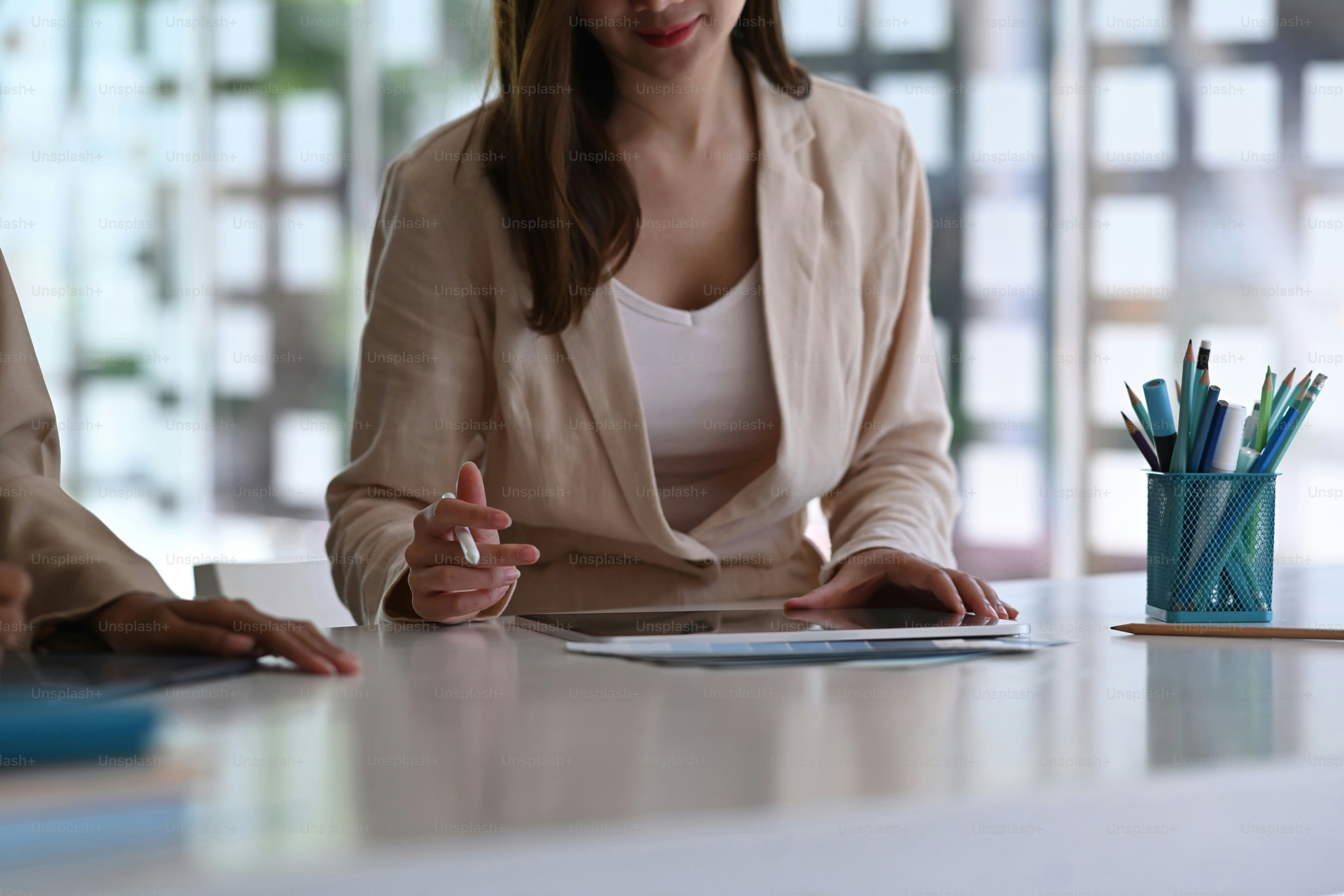 Cropped shot of toe female creative designer working with digital tablet while sitting together at co working table.