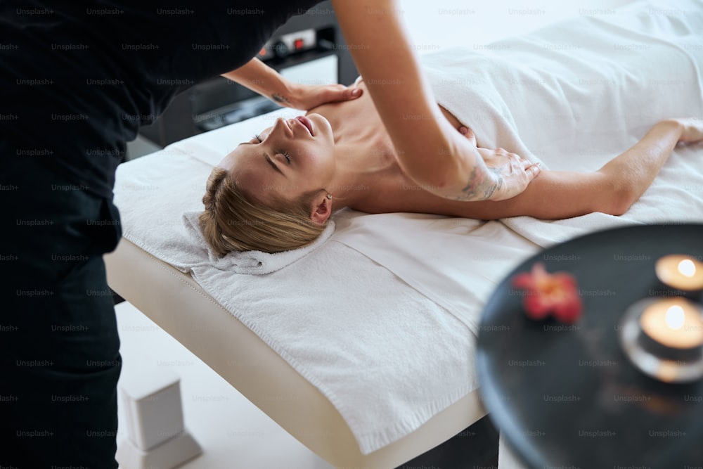 Ritratto di vista laterale se elegante giovane donna caucasica sdraiata sul lettino da massaggio e rilassante alla procedura aromatica in resort