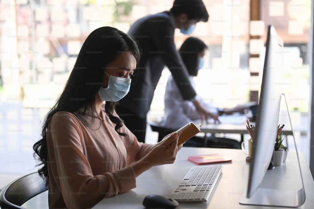 Side view of businesswoman with medical mask working in office.