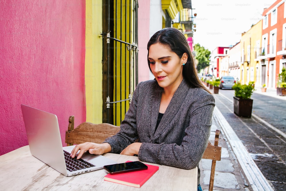 Donna messicana che lavora con il suo computer sulla terrazza di un caffè nelle strade di una città coloniale in America Latina