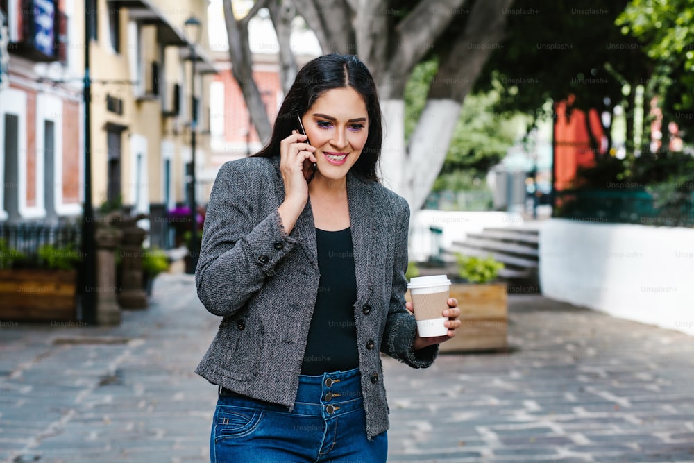 Mexican business woman talking by phone while she is walking in a Latin America city