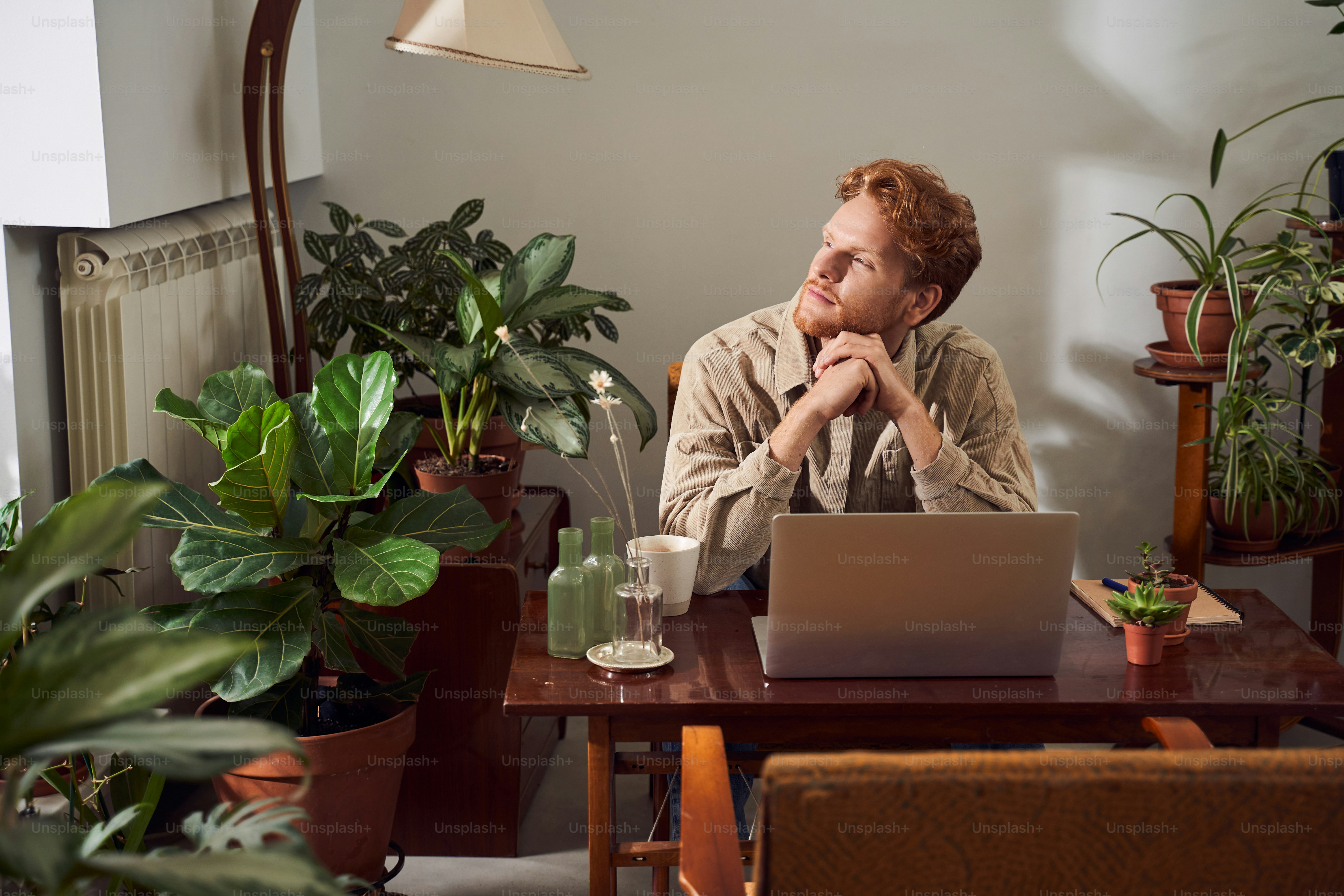 Handsome businessman with red hair sitting at table in front of open laptop