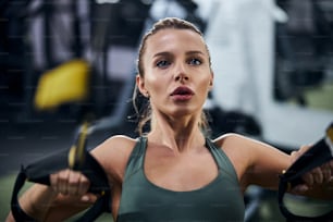Foto de primer plano de una mujer fortaleciendo los músculos de su brazo con la ayuda de tirar de las bandas