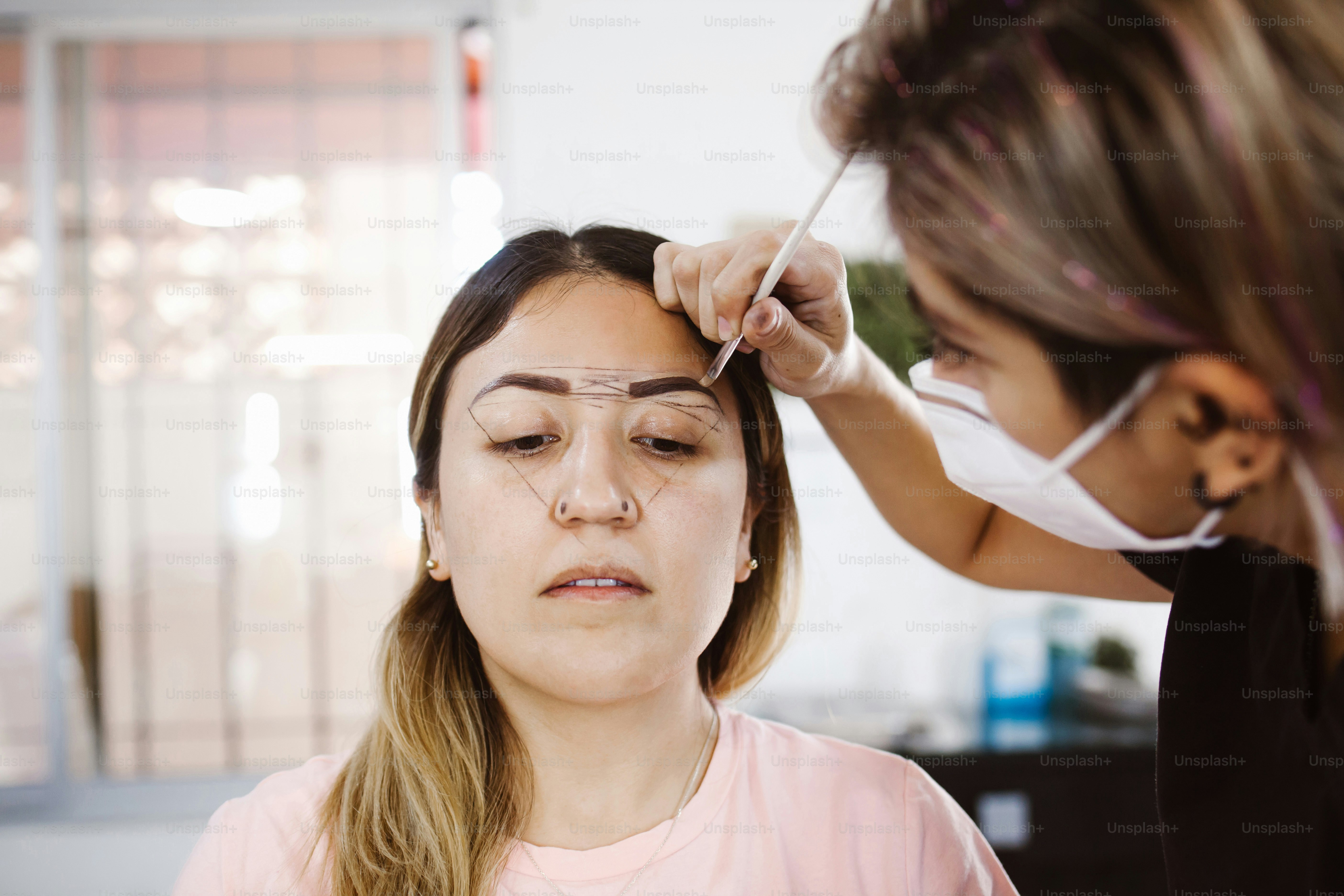 Latin Cosmetologist preparing to mexican woman for eyebrow permanent makeup procedure in Mexico, Microblading closeup