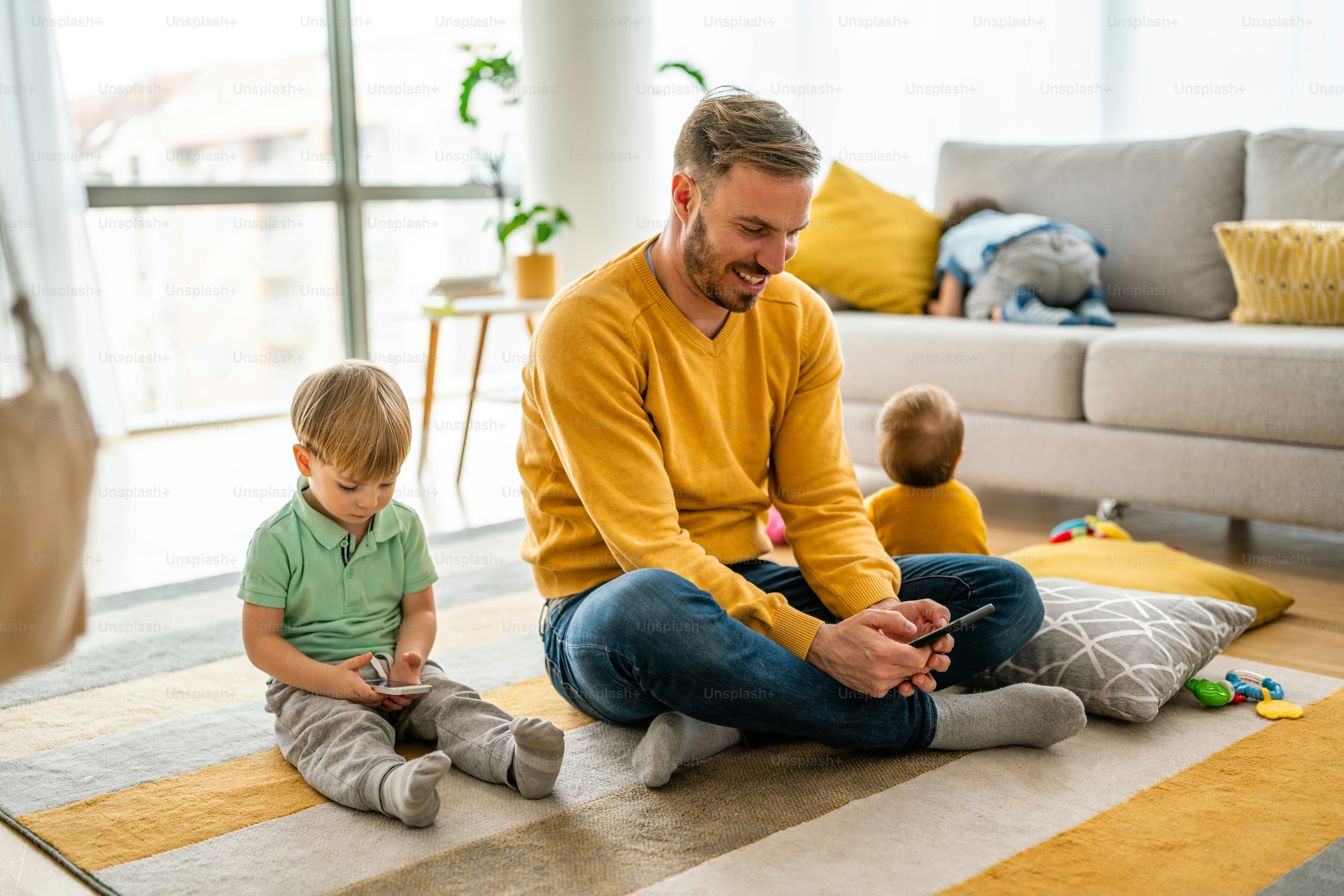 Happy father and son playing games on mobile phone at home. Technology addiction family problem concept