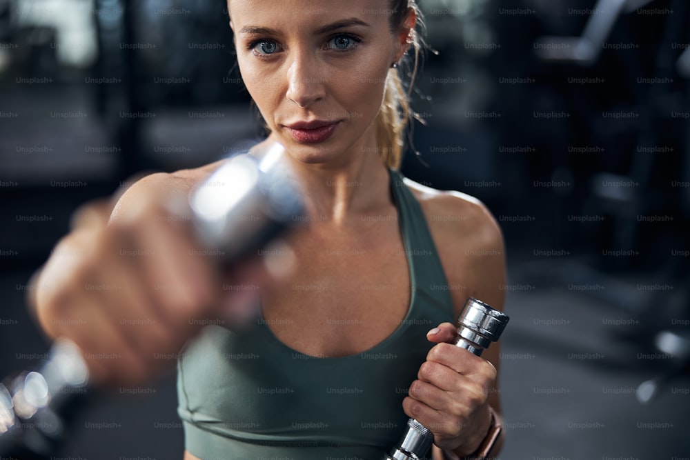Strong-willed person delivering blows with dumbbells during a shadowboxing training in an empty gym