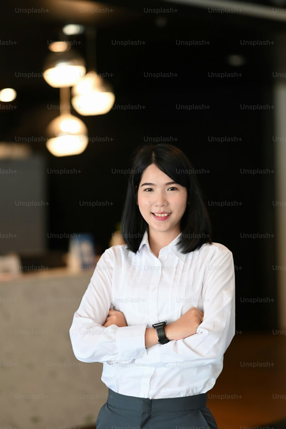Portrait of confident business woman standing with arms crossed in modern office.